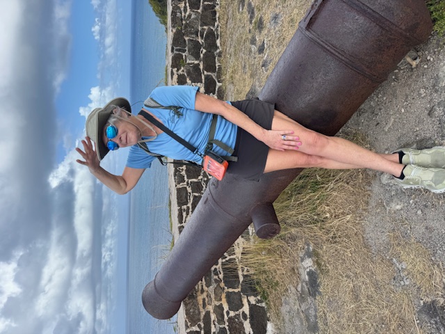 Woman posing beside an old seaside cannon