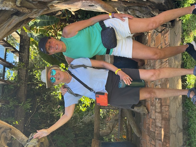 Two women posing under a rustic wooden arch
